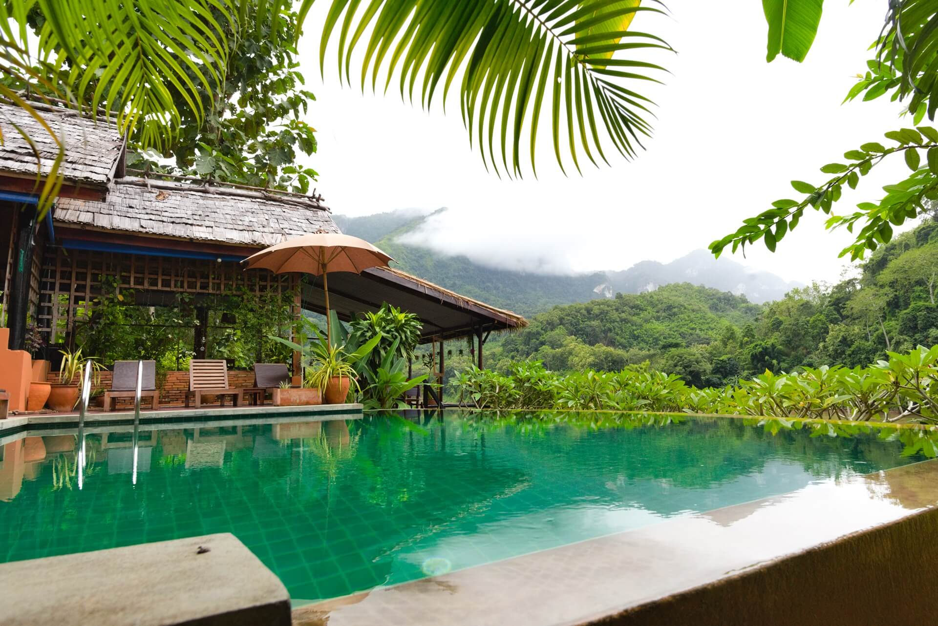 Sharper, optimized view of Mandala Ou Resort's infinity pool overlooking the Nam Ou river and limestone mountains in Nong Khiaw, northern Laos
