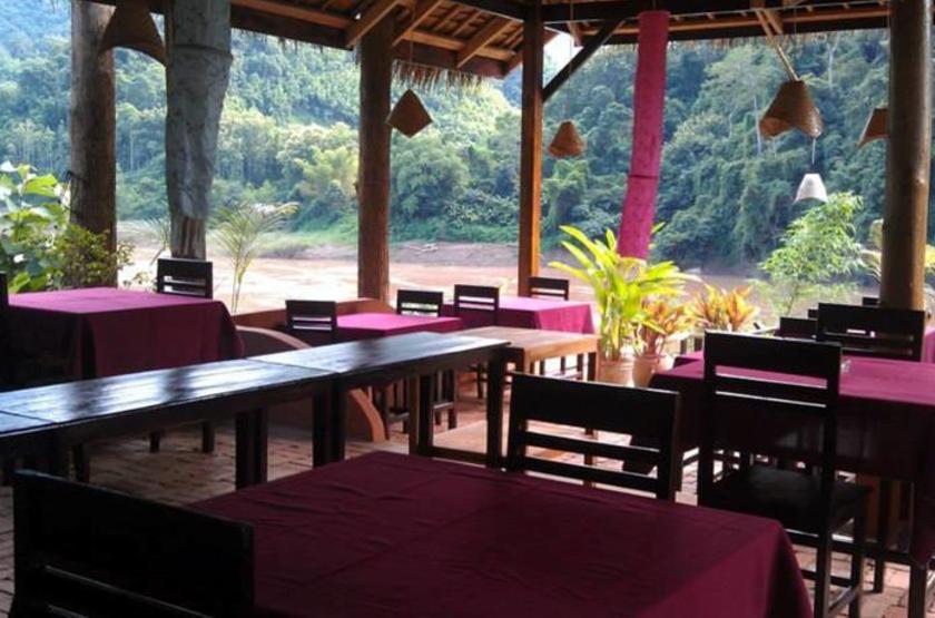 Restaurant dining area showcasing traditional Lao design and river views